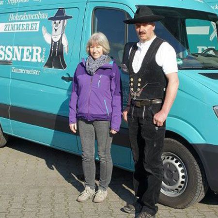 Die Inhaber die vor einen türkisen Transporter stehen.