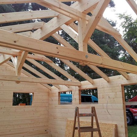 Ein im Bau befindliches Haus, umgeben von Baustellenmaterialien und Gerüsten, zeigt den Fortschritt der Bauarbeiten.