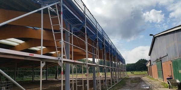 Ein Gerüst wird an einer Scheune montiert, um die Arbeiten an der Gebäudehülle zu erleichtern.