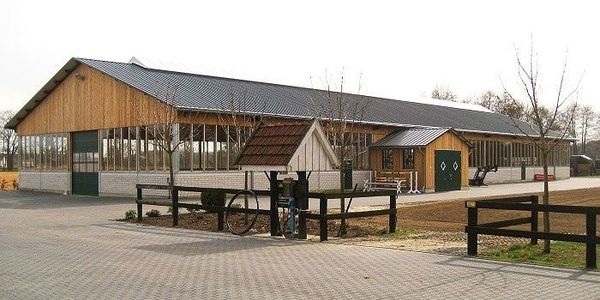 Eine große Halle mit einem Fahrradständer und einem Zaun im Vordergrund.