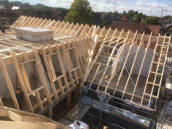 Ein Dach wird mit Holzträgern konstruiert, die sorgfältig platziert und gesichert werden.