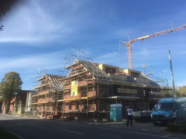 Ein im Bau befindliches Gebäude mit Gerüsten und Kränen, das den Fortschritt der Bauarbeiten zeigt.