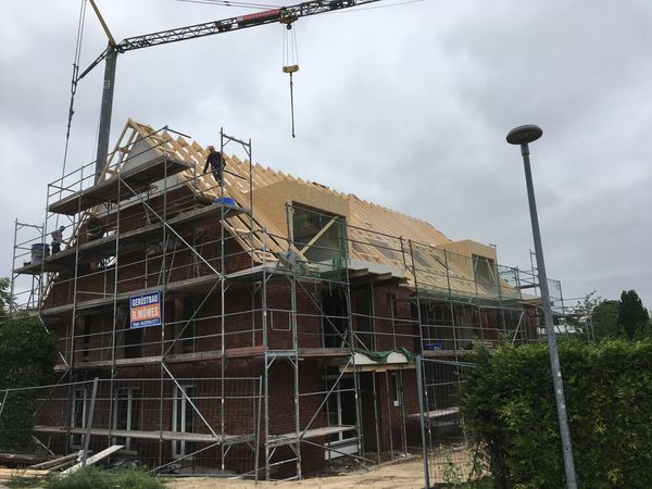 Ein im Bau befindliches Haus mit Gerüst und Kran, das die Fortschritte der Bauarbeiten zeigt.