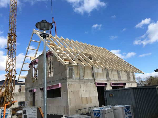 Ein im Bau befindliches Haus mit einem Kran und einem Dach, das auf die Fertigstellung wartet.