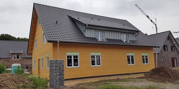 Ein gelbes Haus mit dunkelgrauen Dachziegeln