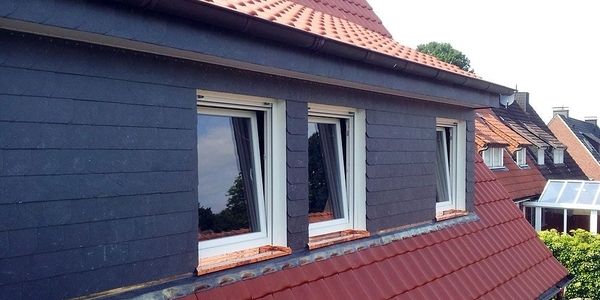 Eine Nahaufnahme eines dunkelgrauen Hauses mit roten Dachziegeln.