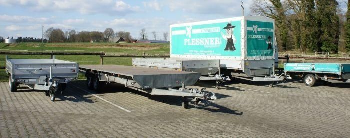 Mehrere Anhängerarten stehen auf einem Parkplatz, umgeben von Bäumen und einer klaren Himmelansicht.