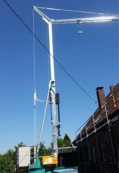 Ein Kran hebt ein großes Objekt an, während er auf einer Baustelle positioniert ist.