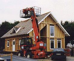 Holzrahmenbau eines Hauses mit roten Teleskopkran davor