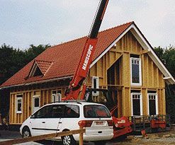 Holzrahmenbau eines Hauses mit roten Teleskopkran davor