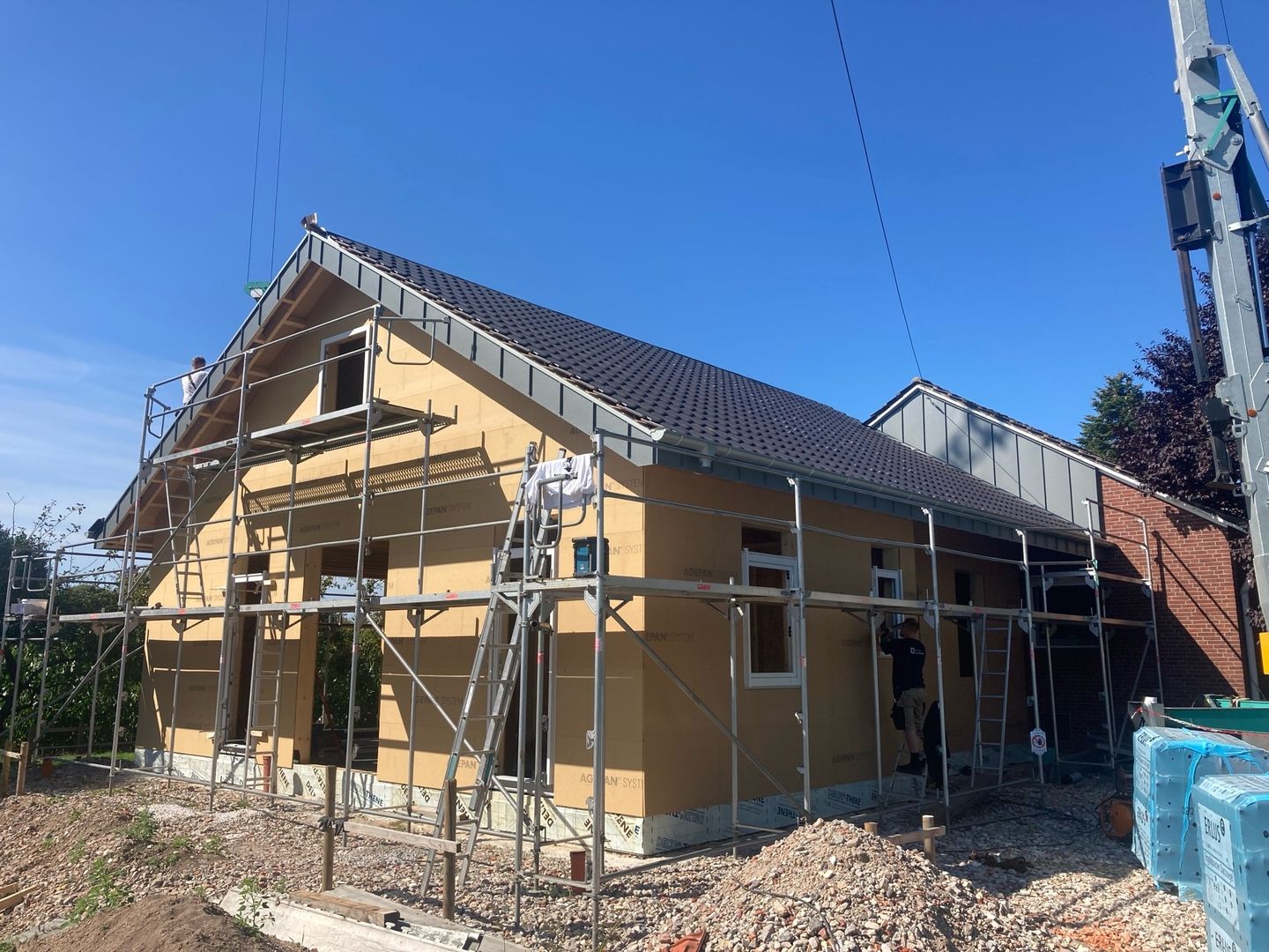 Ein Haus, das gerade gebaut wird, mit einem Gerüst auf dem Dach zur Unterstützung der Bauarbeiten.