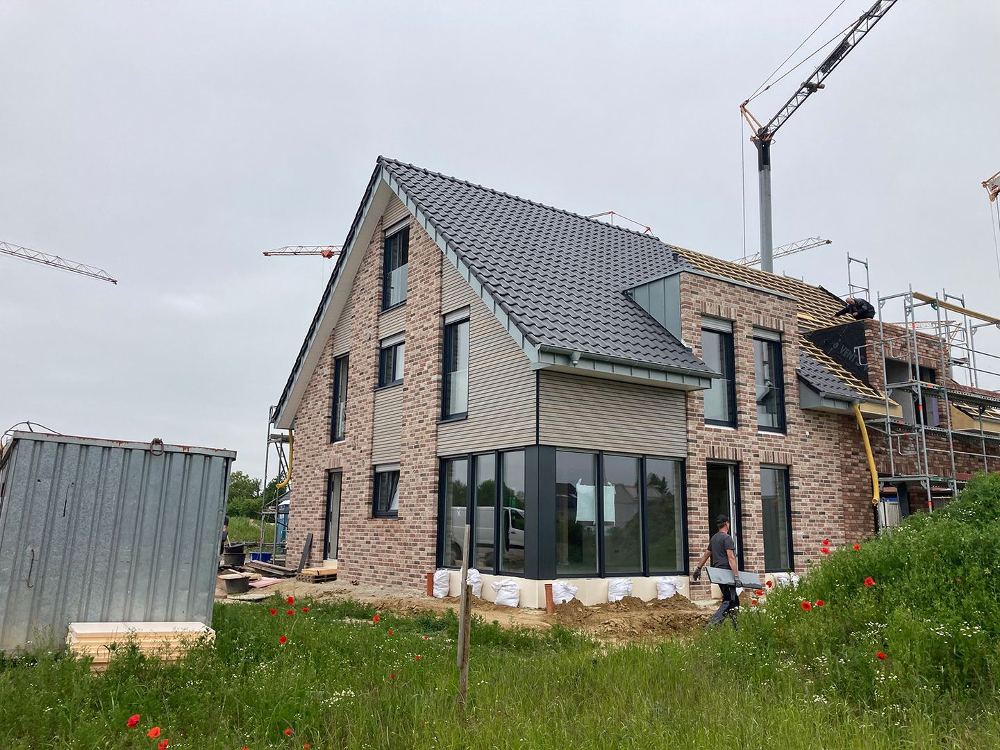 Ein Haus im Bau, das durch ein großes Fenster Licht und Ausblick auf die Umgebung bietet.