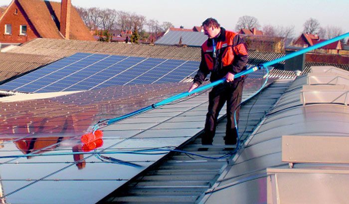 Ein Mann reinigt ein Solarpanel mit einer Bürste.